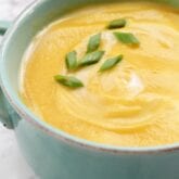 A bowl of butternut squash soup in a blue bowl.