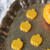 Turmeric gummies in a pumpkin shape on a brass platter.