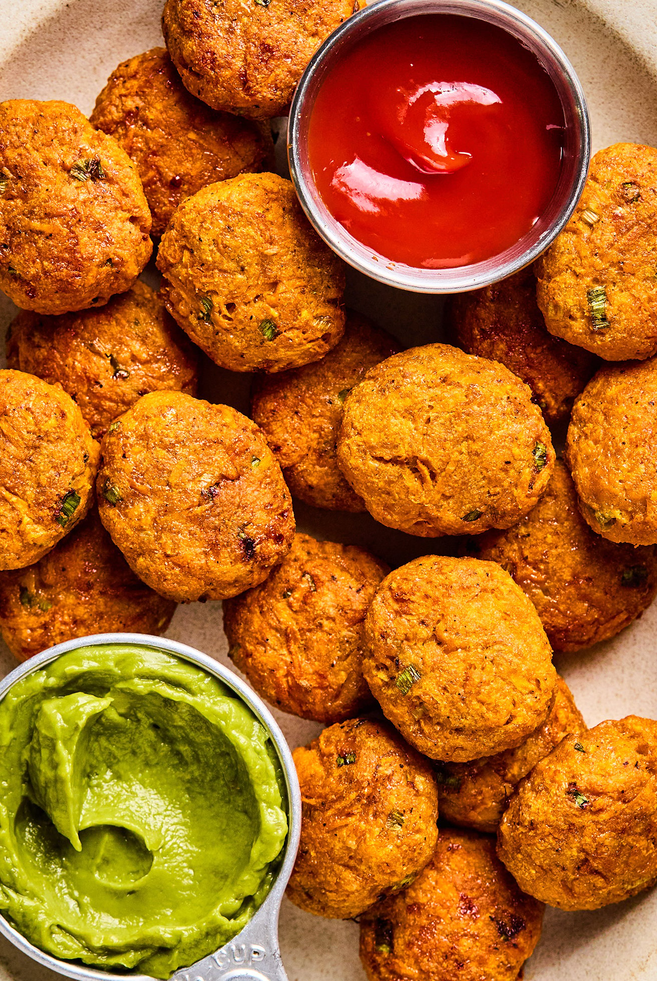 Sweet potato chicken poppers on a plate with a side of ketchup and guacamole. 