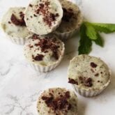 Several mint ice cream cups sitting on a counter with fresh mint.