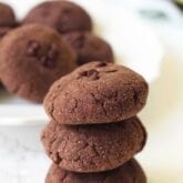 A stack of avocado cookies with a plate of avocado cookies behind them