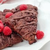 A white plate with paleo chocolate raspberry scones on it with fresh raspberries on top.