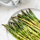 A white plate filled with fresh roasted aspargus.