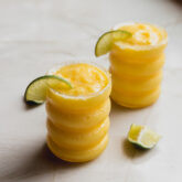 Two glasses of frozen mango margarita mocktail with lime slices.