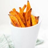 A white cup filled with sweet potato fries.