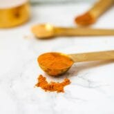A few measuring spoons filled with spices to make a turmeric iced latte.