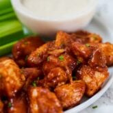 A plate with bbq chicken poppers on it next to dipping sauce.