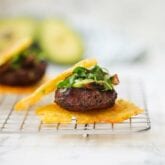 A tostone slider topped with avocado and greens on a wire rack.