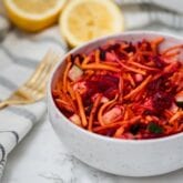 A bowl of detox carrot slaw with a fork next to it.
