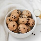 A white bowl filled with cookie dough protein bites in it.