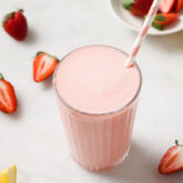 Straw in a tall glass of creamy frozen pink lemonade.