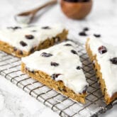 A wire rack with three pieces of cranberry bliss bars resting on it.