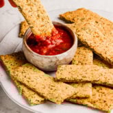 Plate of cauliflower breadsticks with a bowl of sauce.
