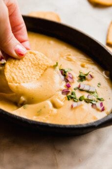 Grain free chip dipping into dairy free queso.