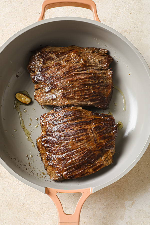 The steak cooking in a pan.