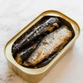 A open container of sardines sitting on a counter.
