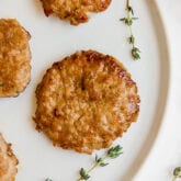 A white plate with homemade sausage patties on it.