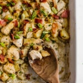 A baking dish filled with chicken bacon ranch casserole with a wooden spoon taking some out.
