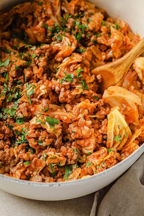 Unstuffed cabbage roll in a dutch oven with a wooden spoon.