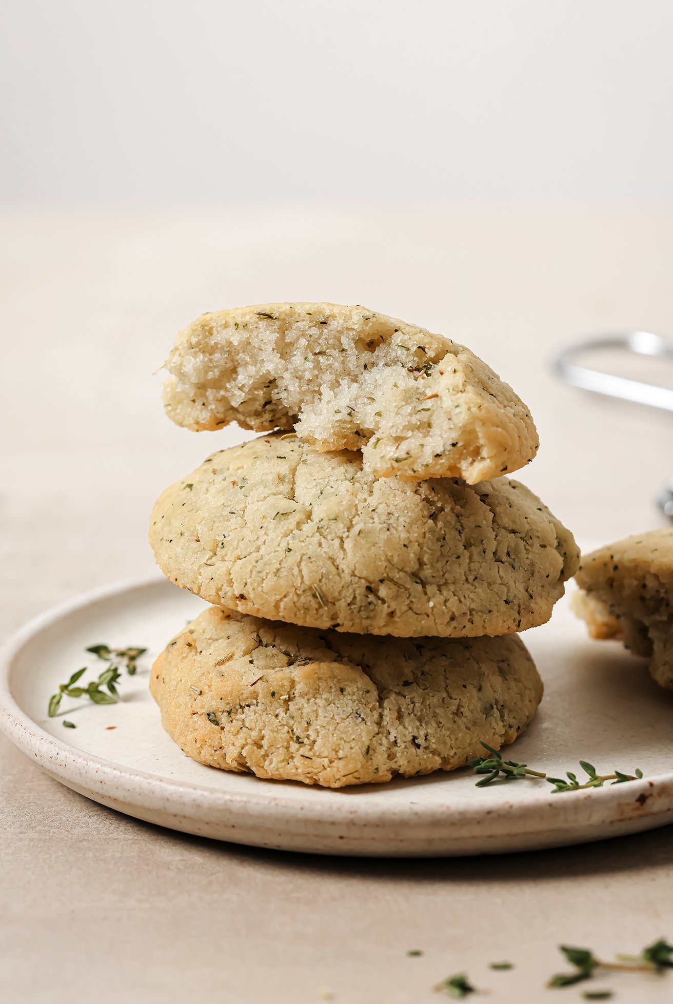 Stack of three garlic & herb rolls on a white plate with thyme on the side.