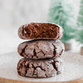A stack of chocolate crinkle cookies with a bite taken out of the top one.