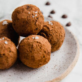 A speckled ceramic plate topped with chocolate avocado protein truffles.