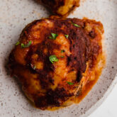 A plate with an oven baked bbq chicken thigh on it.