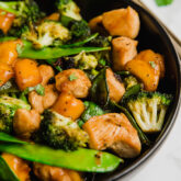 A black bowl filled with mango chicken stir fry.