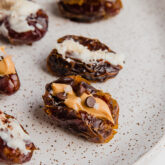 A white plate filled with almond butter and coconut butter stuffed dates.