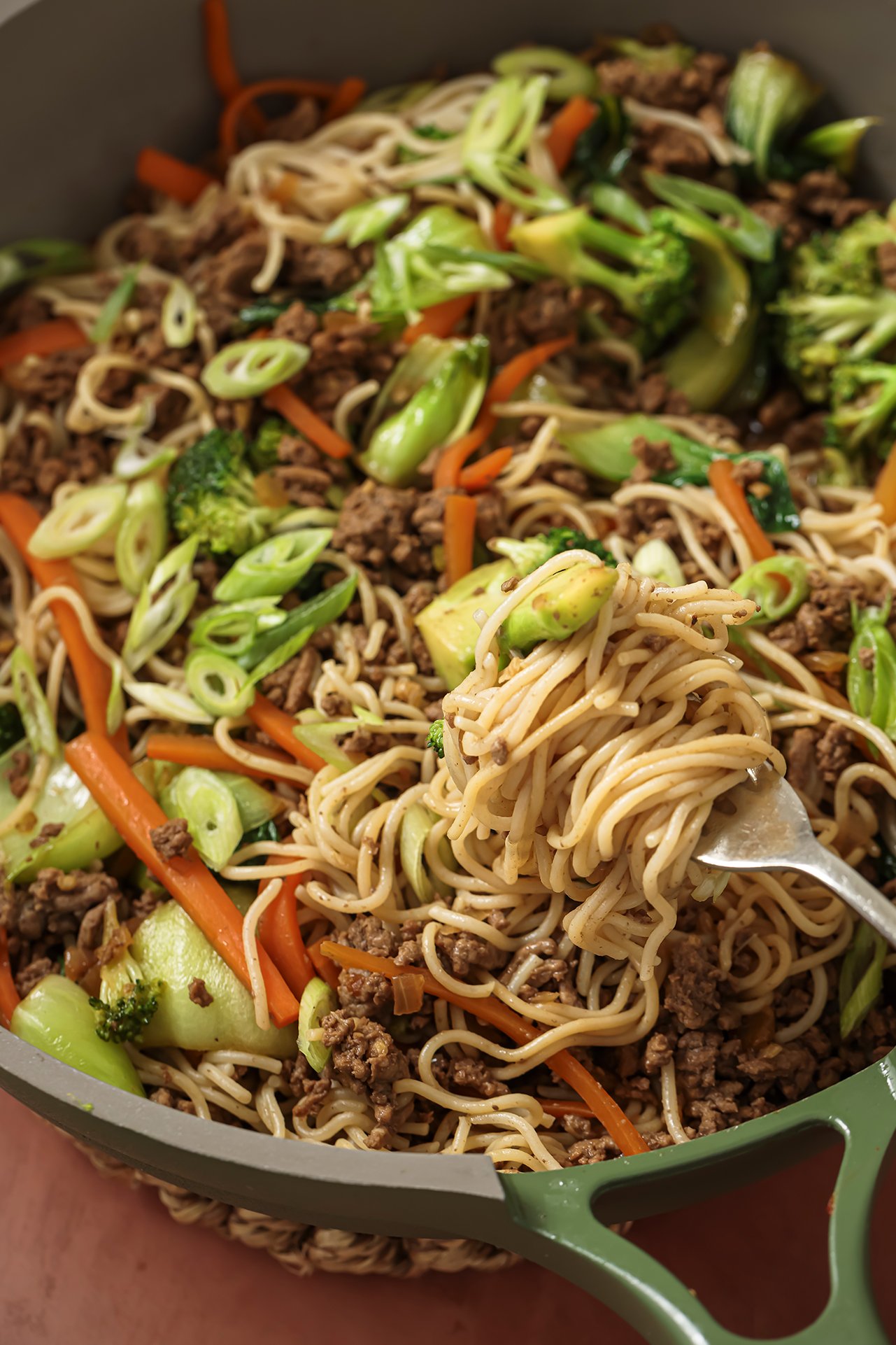 A fork digging into a pan of ground beef ramen noodle stir fry.