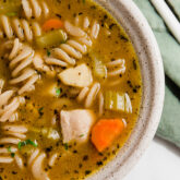 A white bowl filled with chicken noodle soup.