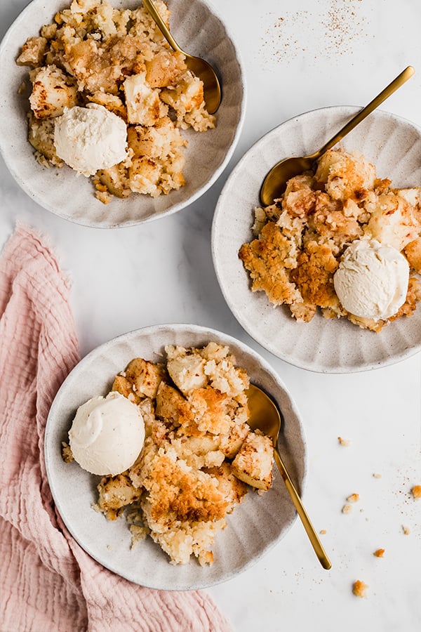 apple crisp on plates with spoons and vanilla ice cream