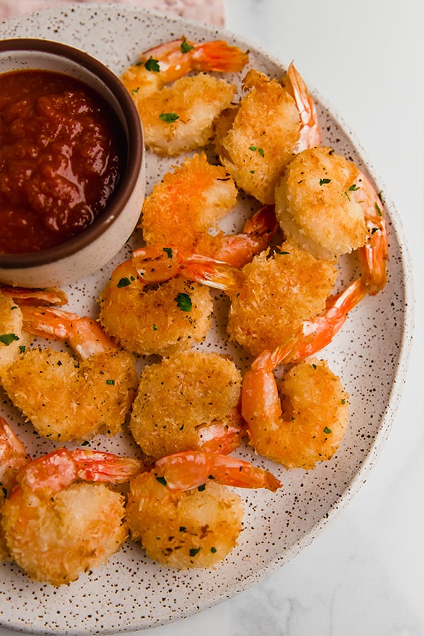 oven-baked coconut shrimp on plate with cocktail sauce
