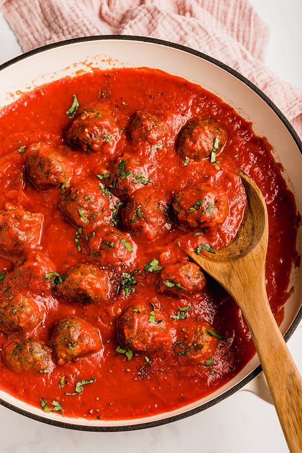 oven-baked meatballs in skillet with wooden spoon