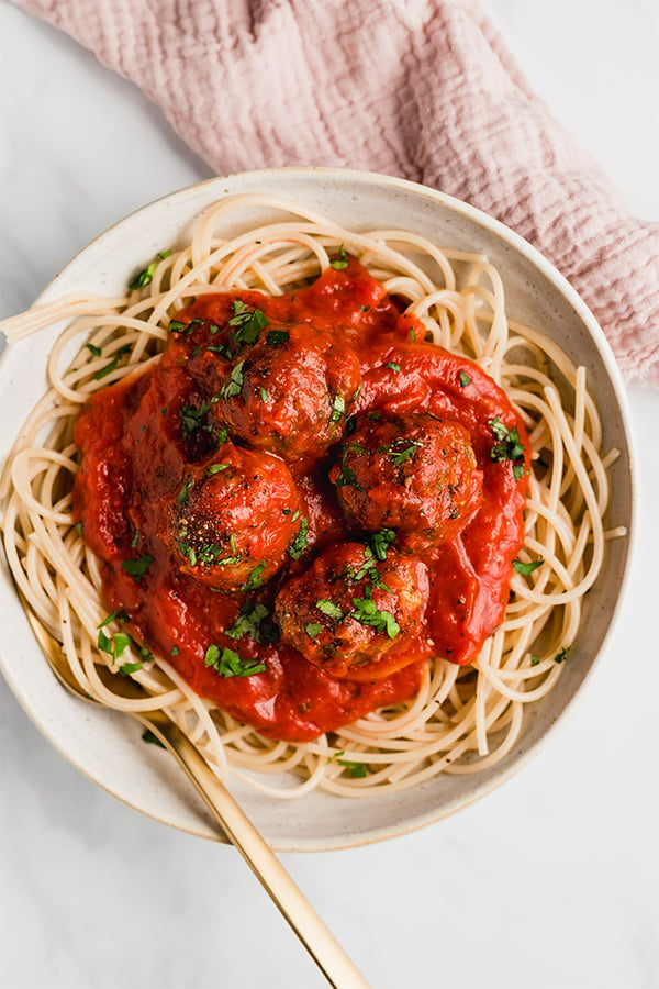 spaghetti and meatballs in a bowl with a fork