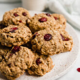 Oatmeal cranberry cookies on a platter with a glass of milk in the background.