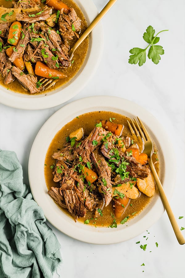 slow cooker pot roast in bowls with forks