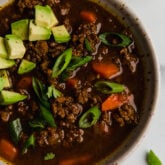 Asian chili topped with avocado in a bowl.