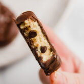 Person holding a chocolate covered cookie dough Easter egg missing a bite.
