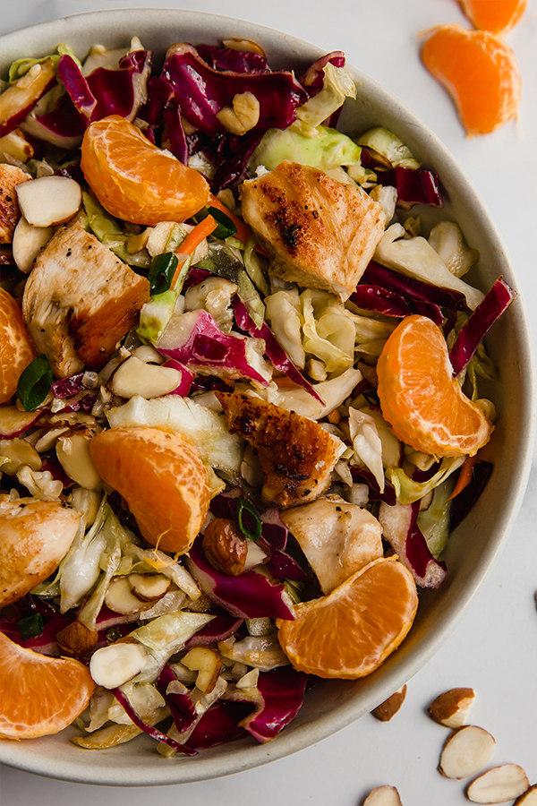 chinese chicken salad in bowl with mandarin orange slices on top