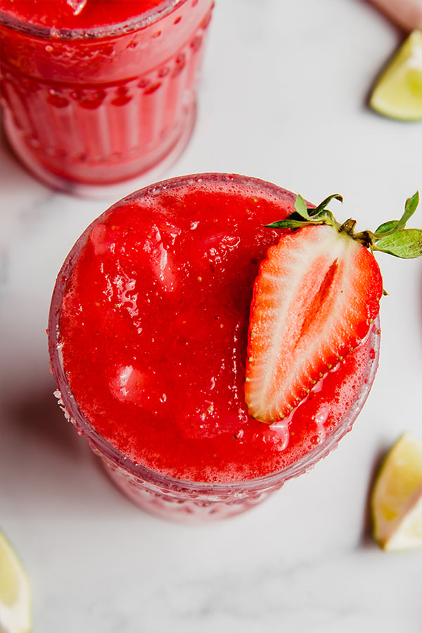 Top view of strawberry margarita in a glass with a strawberry on top