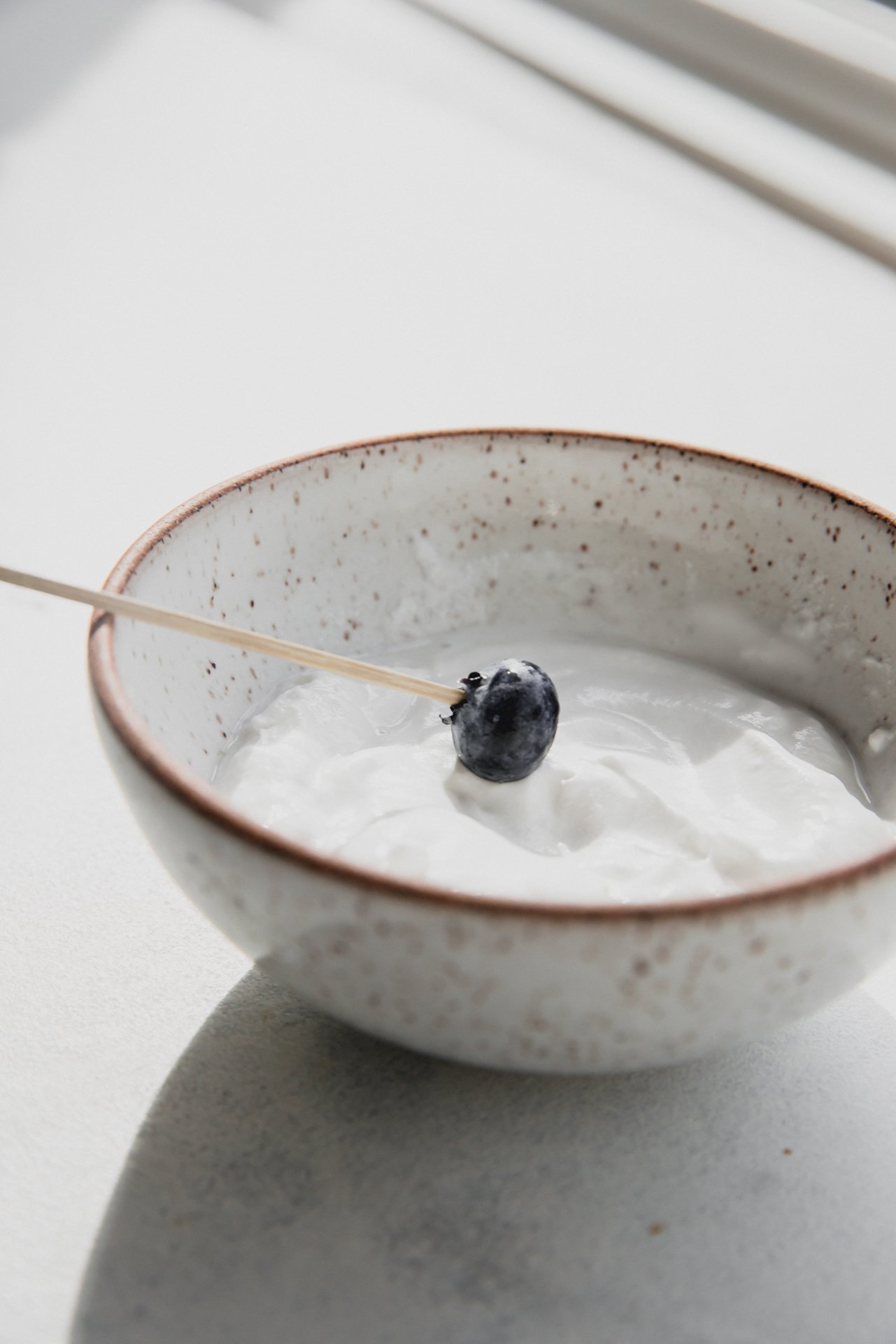 Blueberry on a tooth pick dipping in yogurt. 