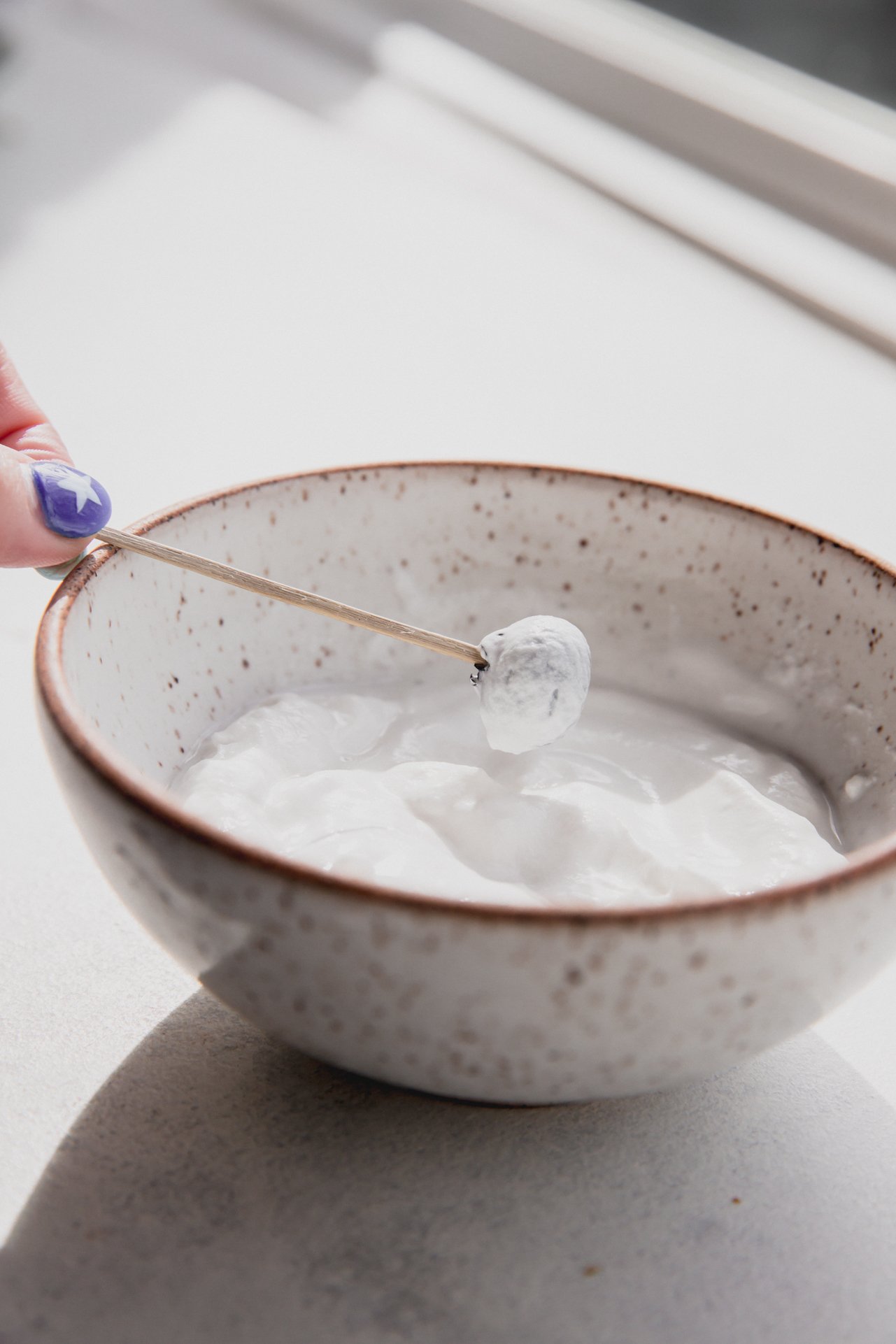 Blueberry on a toothpick coated in yogurt.