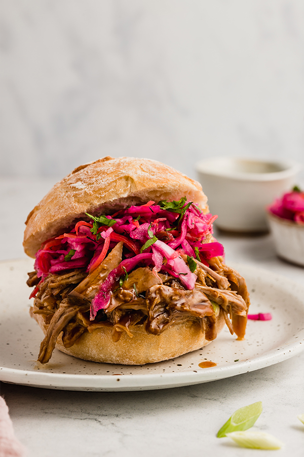 bbq pulled pork served on a sourdough bun with toppings on a plate