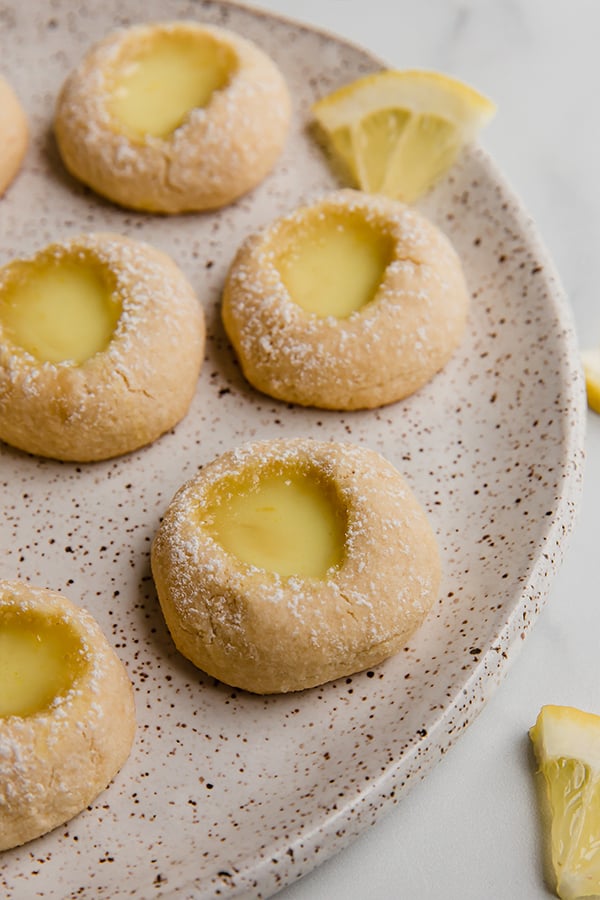 Lemon thumbprint cookies on a plate with powdered sugar on top