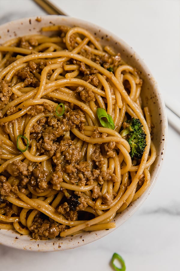 Mongolian ground beef with noodles served in a bowl with chopsticks