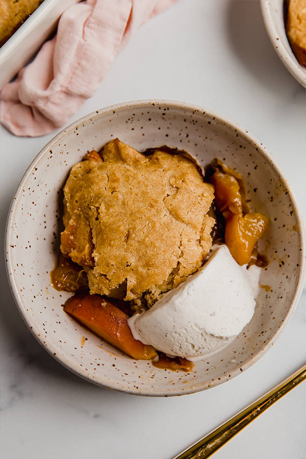 Top view of cooked peach cobbler with vanilla dairy free ice cream