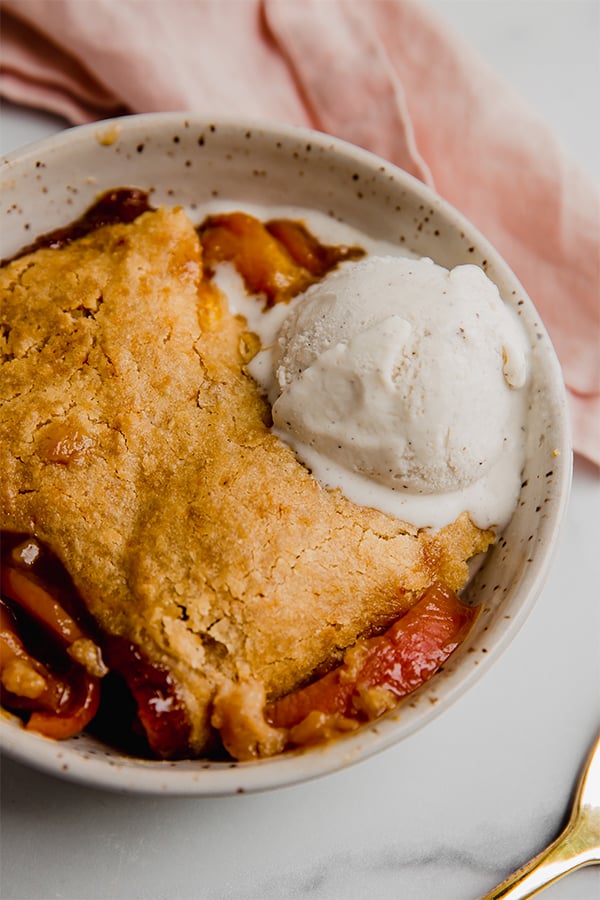 Peach cobbler in a bowl with dairy free ice cream