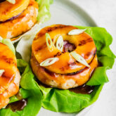 Sweet and sour chicken burgers topped with a pineapple slice.