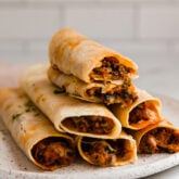 Gluten-free pizza roll ups stacked on a plate.